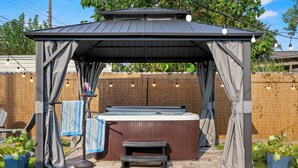 A covered hot tub area with a pergola, a bench, and string lights. - Walk 2 Beach-Hot Tub-2 King beds-Waffle bar-Bikes (Galveston)