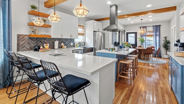 A modern kitchen with a central island, bar stools, pendant lighting, and wooden beams. - Walk 2 Beach-Hot Tub-2 King beds-Waffle bar-Bikes (Galveston)