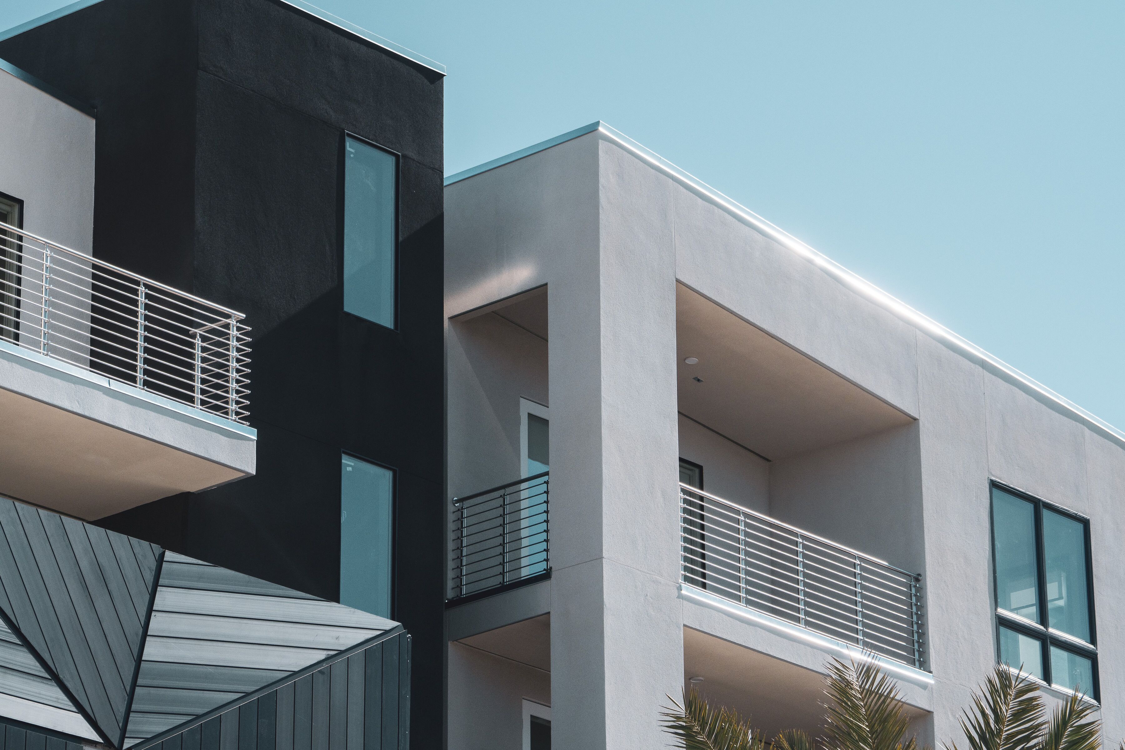 A modern building with a geometric facade, balconies with metal railings, and large windows.