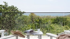 Terraza de madera con una mesa y sillas, con vista a un paisaje exuberante.