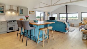 A modern kitchen with a central island, bar stools, and a dining table.
