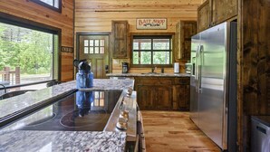 A kitchen with wooden walls, a stainless steel refrigerator, a stove, and a sign that reads "Bait Shop." - Great Views, High Speed Internet, Hot Tub, Fireplace, Balcony, Sauna, Loft! (Broken Bow)