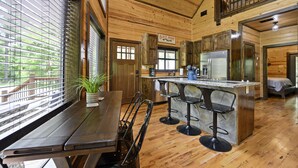 A wooden interior with a kitchen area, bar stools, and a sign reading "Bait Shop". - Great Views, High Speed Internet, Hot Tub, Fireplace, Balcony, Sauna, Loft! (Broken Bow)