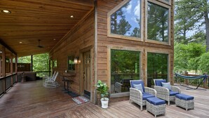 A wooden deck with wicker furniture and a hammock. - Great Views, High Speed Internet, Hot Tub, Fireplace, Balcony, Sauna, Loft! (Broken Bow)