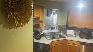 Una cocina con armarios de madera, lavavajillas de acero inoxidable, microondas y un fregadero.
