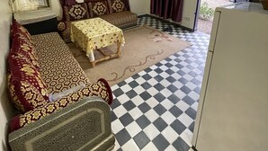 A room with a checkered floor, a sofa, a table, and purple curtains. - Dar izniren (Ourika)