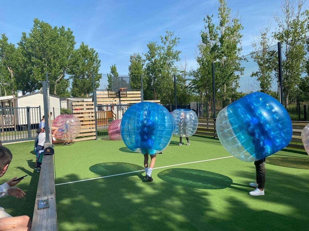 A playground with a green surface and a fence.