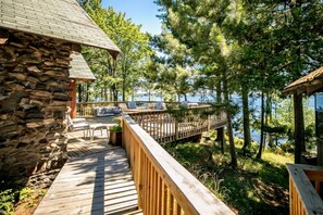 A stone building with a wooden deck leading to a dock over water, surrounded by trees. - Private Island Estate on Lake Vermilion (Cook)