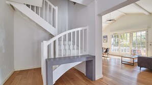 A modern interior with a wooden staircase, a grey console table, and a living area with a sofa and a coffee table. - Villas Odalys Domaine de Lana (Urrugne)
