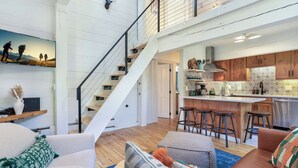 A spacious living area with a staircase, a kitchen with bar stools, and a dining area.