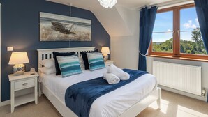 Ein Schlafzimmer mit einem Bett, zwei Nachttischen mit Lampen, einer Deckenleuchte, einem Fenster mit Vorhängen und einem Bild an der Wand.