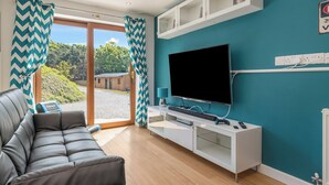Ein modernes Wohnzimmer mit einer Couch, einem Flachbildfernseher, einer Spielkonsole und einer weißen Unterhaltungsanlage.