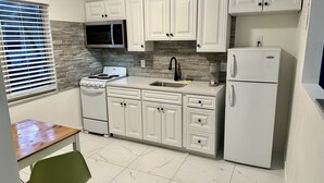 A compact kitchen with white cabinets, a stove, microwave, sink, and refrigerator. - Sapphire by the Sea Unit 9 - King Pool View Suite King, kitchen, heated pool  (Fort Lauderdale)