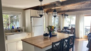 A modern kitchen with white cabinets, a wooden island, and pendant lighting.