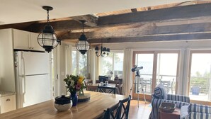 A spacious kitchen with a wooden island, white cabinets, and a dining area with a striped sofa and table.