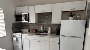 Une cuisine moderne avec des meubles blancs, un réfrigérateur en acier inoxydable, un four à micro-ondes, une cuisinière et un évier.