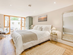 Une chambre à coucher avec un grand lit, une table de chevet avec des lampes, un miroir et une vue sur l’extérieur grâce à une porte coulissante.