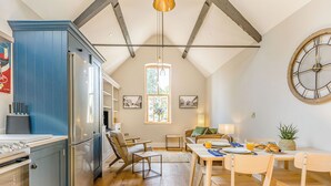 A kitchen with a blue cabinet, a dining area with a table and chairs, and a large clock on the wall. - 1 bedroom accommodation in Bidford On Avon (Bidford On Avon)
