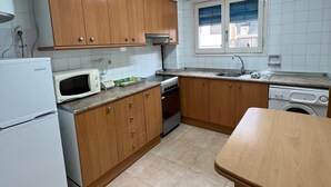 A kitchen with wooden cabinets, a microwave, stove, sink, and a washing machine.