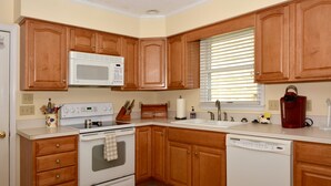 A kitchen with wooden cabinets, a white microwave, a stove, and a dishwasher. - Walk Everywhere! Pet Friendly Rehoboth Beach Home Sleeps 10 (Rehoboth Beach)