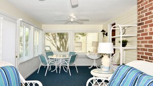 A sunlit patio with white wicker furniture, a ceiling fan, and a brick wall. - Walk Everywhere! Pet Friendly Rehoboth Beach Home Sleeps 10 (Rehoboth Beach)