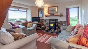 A cozy living room with a stone fireplace, comfortable seating, and a television. - 3 bedroom accommodation in Druidstone Cross - near Nolton Haven (Haverfordwest)