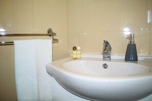 A bathroom with a white sink, a towel rack, and toiletries. - Casa Belos Ares (Peniche)