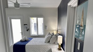 Camera da letto con un letto, comodino, lampada e ventilatore a soffitto.