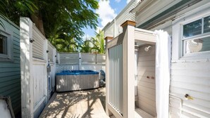 Ein überdachter Außenbereich mit Whirlpool, Holzterrasse und einem Gebäude mit Fenster.