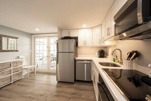 A modern kitchen with stainless steel appliances, a dishwasher, and a large window.