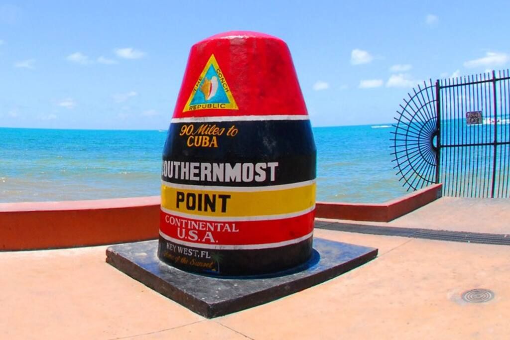A cylindrical monument with text indicating it is the Southernmost Point in the Continental U.S.A., located in Key West, Florida.