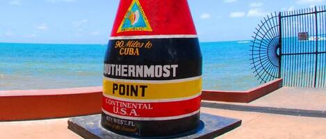 A cylindrical monument with text indicating it is the Southernmost Point in the Continental U.S.A., located in Key West, Florida.