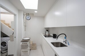 A modern kitchen with a built-in washing machine, a sink, and a clock on the wall. - House with 1 bedroom, 1 bathroom and terrace near the sea (Can Picafort)