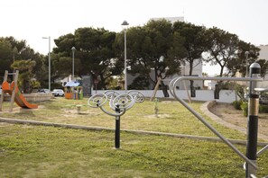 A playground with a slide and swings, surrounded by trees and a lamp post. - House with 1 bedroom, 1 bathroom and terrace near the sea (Can Picafort)