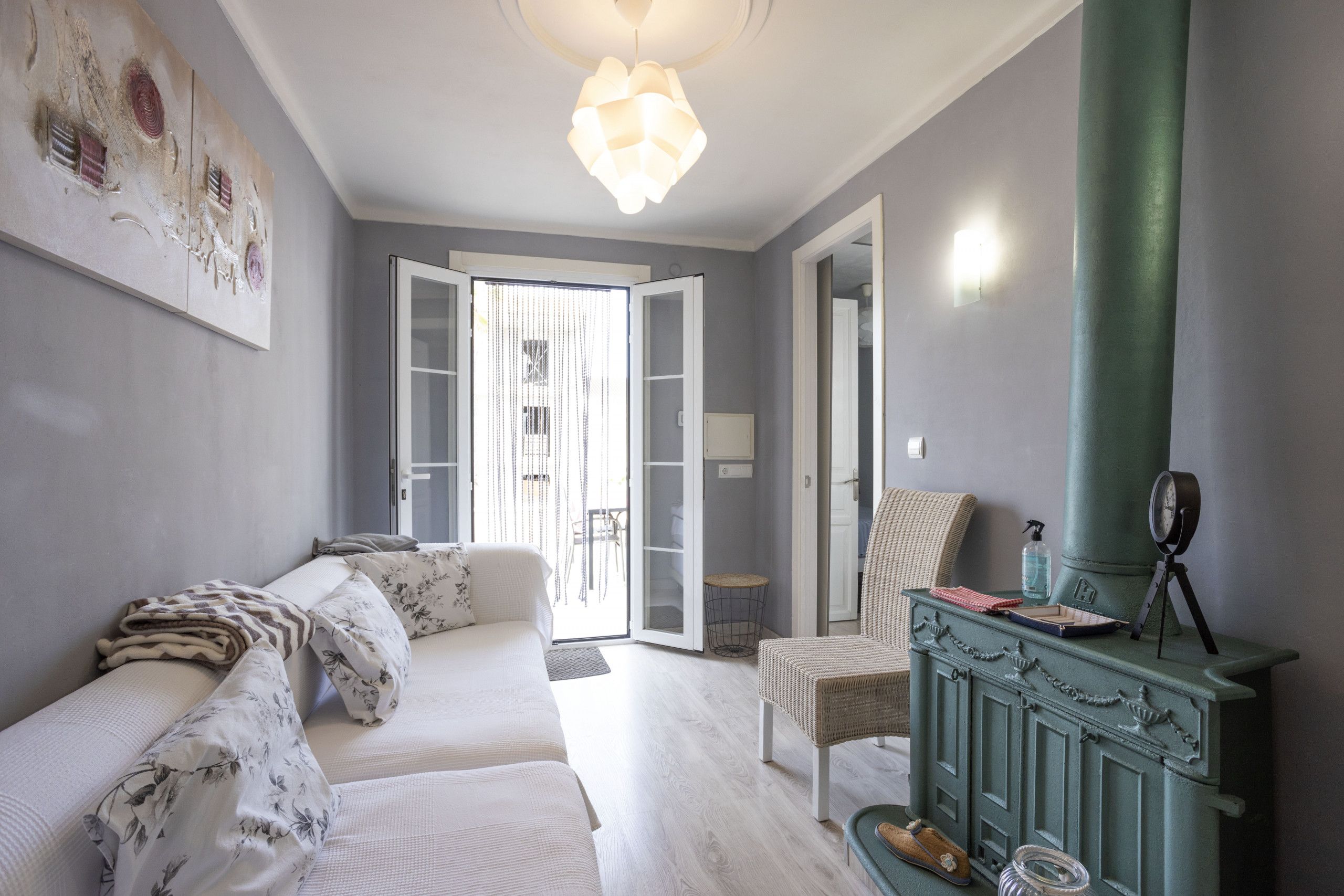 Ein Schlafzimmer mit einem Bett, einem Sessel, einem grünen Herd und einer Tür, die auf einen Balkon führt.