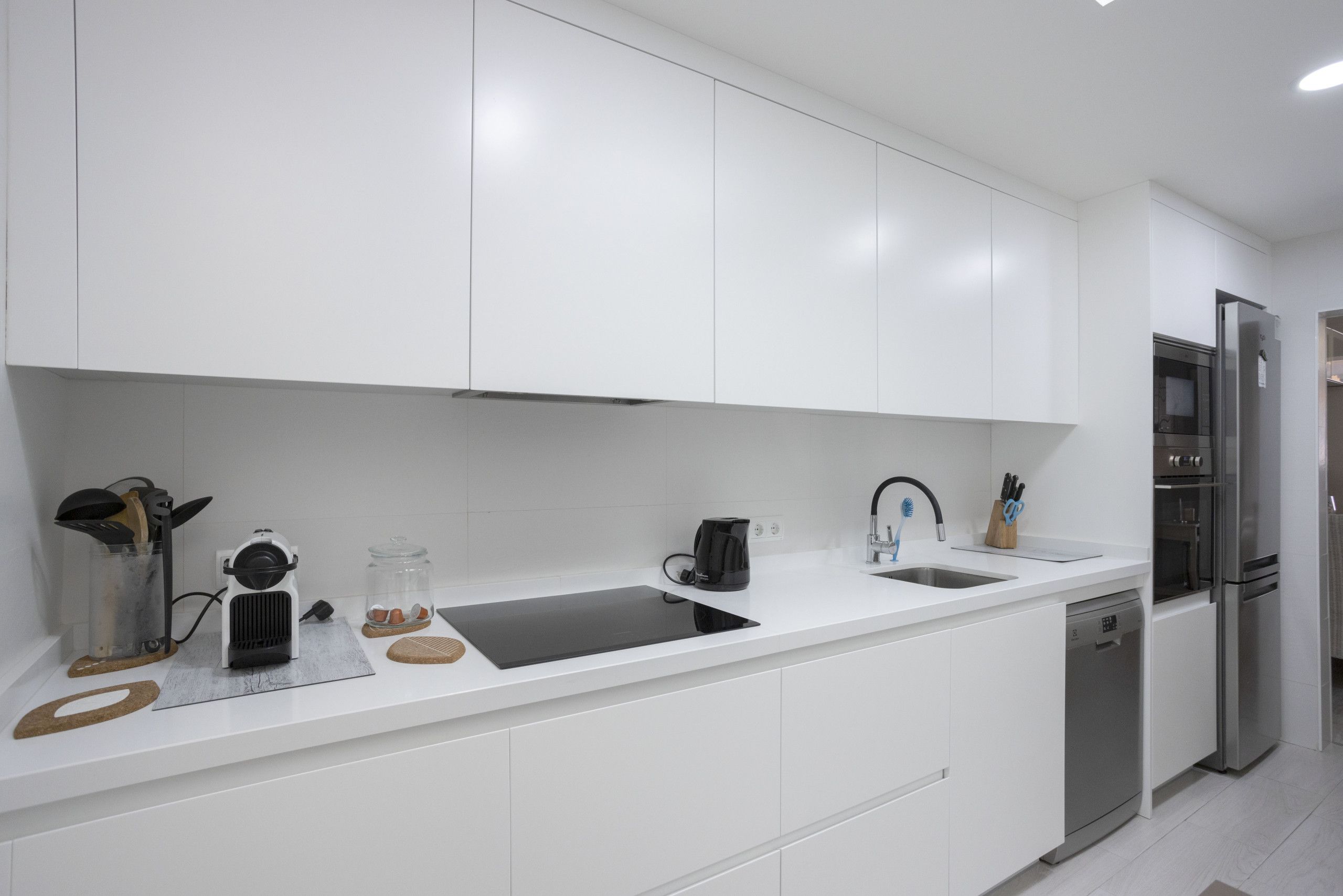 Una cucina moderna con mobili bianchi, un frigorifero in acciaio inossidabile e una lavastoviglie integrata.