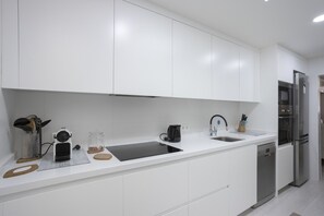 A modern kitchen with white cabinetry, a stainless steel refrigerator, and a built-in dishwasher. - House with 1 bedroom, 1 bathroom and terrace near the sea (Can Picafort)