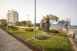 A park with a large stone sculpture, a paved walkway, and a building in the background. - House with 1 bedroom, 1 bathroom and terrace near the sea (Can Picafort)
