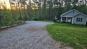 A house with a gravel driveway, surrounded by a forest.