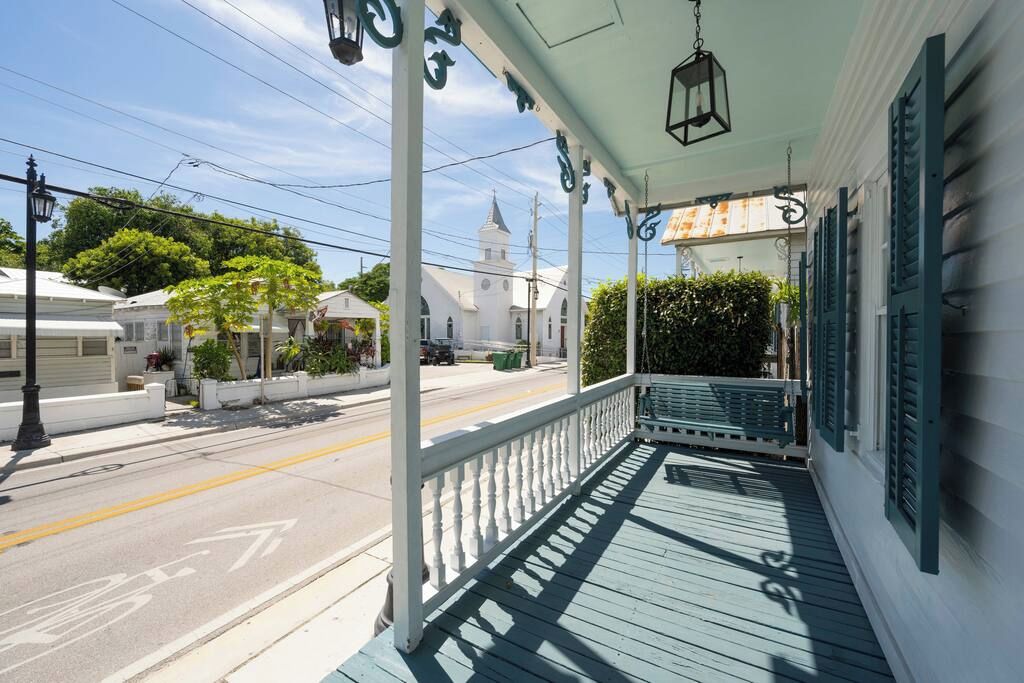 A porch with a railing, a bench, and a hanging lantern.