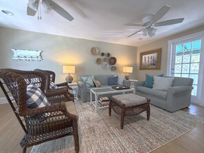 A living room with wicker furniture, a grey sofa, and a ceiling fan.