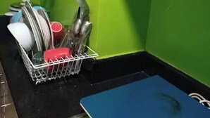 A kitchen with green walls, a black countertop, and a blue cutting board. - MOA VIEW 16TH flr unit (Pasay)