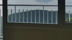 Een kamer met een groot raam, met uitzicht op verre bergen en een wateroppervlak.