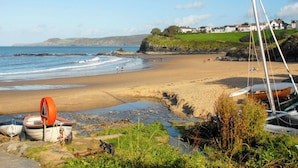 A beach with boats, a sailboat, and houses in the background. - Spacious Teifi Valley barn for holidays near the Cardigan coast. (Cenarth)