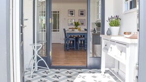Eine moderne Küche mit Essbereich, mit Holzboden, weißen Schränken und einem Blumentopf auf der Arbeitsfläche.