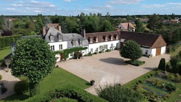 Stately building with a traditional facade, surrounded by a beautifully maintained garden and other historic structures.