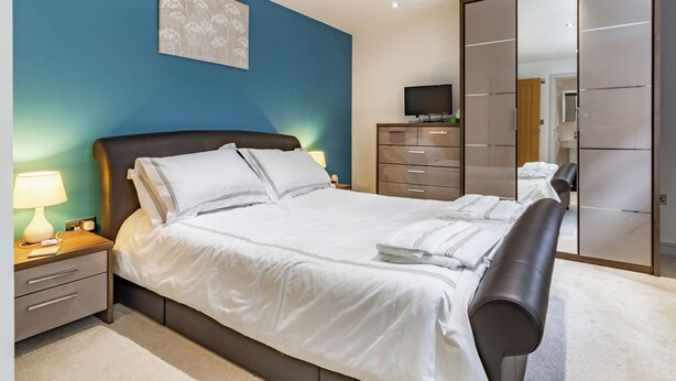 Una camera da letto moderna con un letto, comodini, una TV e un armadio.