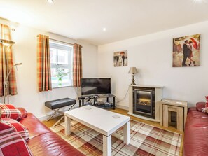 A living room with a sofa, a television, a fireplace, and a painting on the wall.