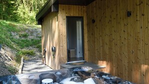 A wooden cabin with a hot tub and a door leading inside.