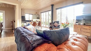 A modern living room with a large sofa, a television, and a dining area with chairs and a table.